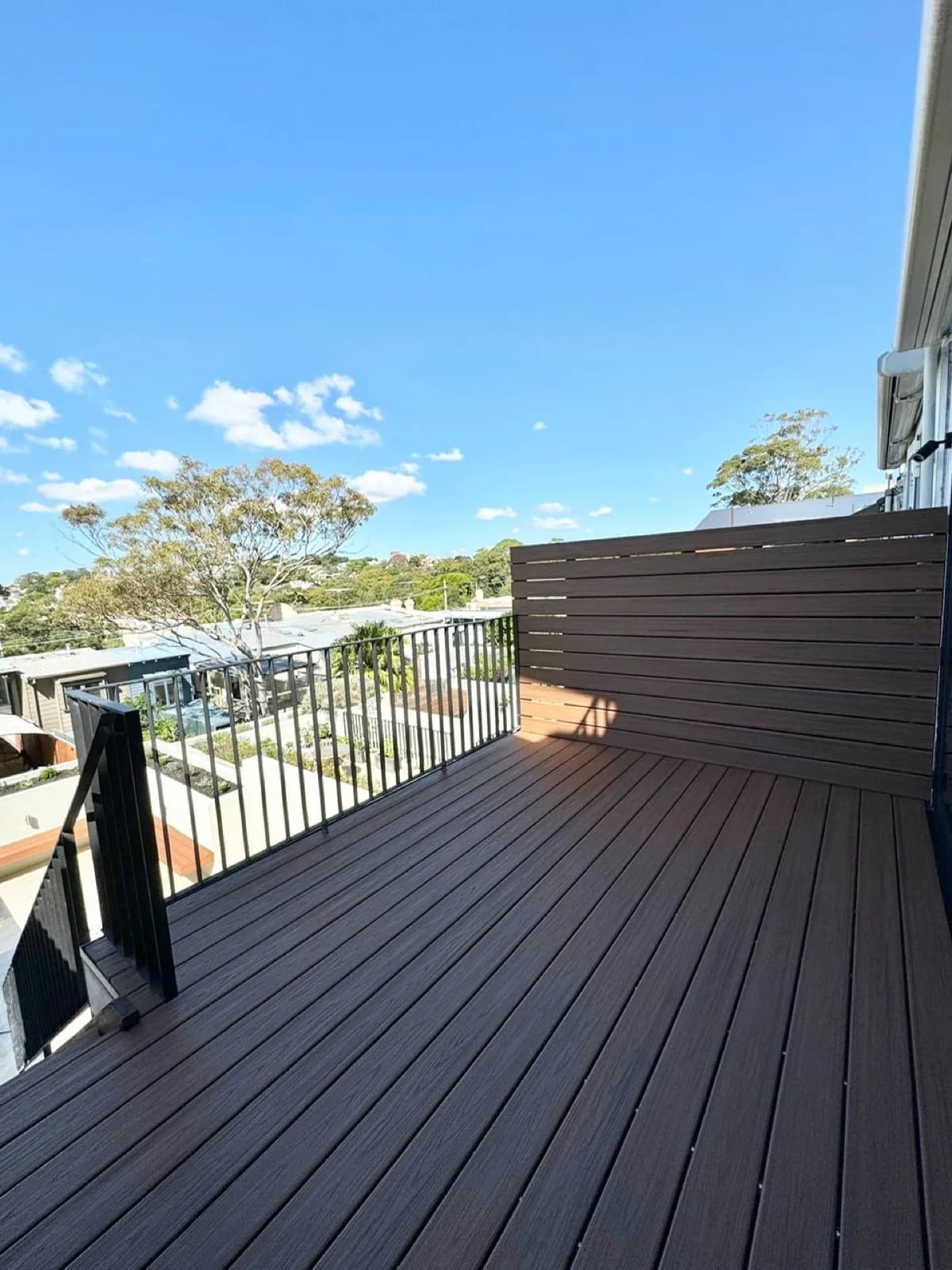 Upper balcony composite deck with composite privacy screen and black railing, city views