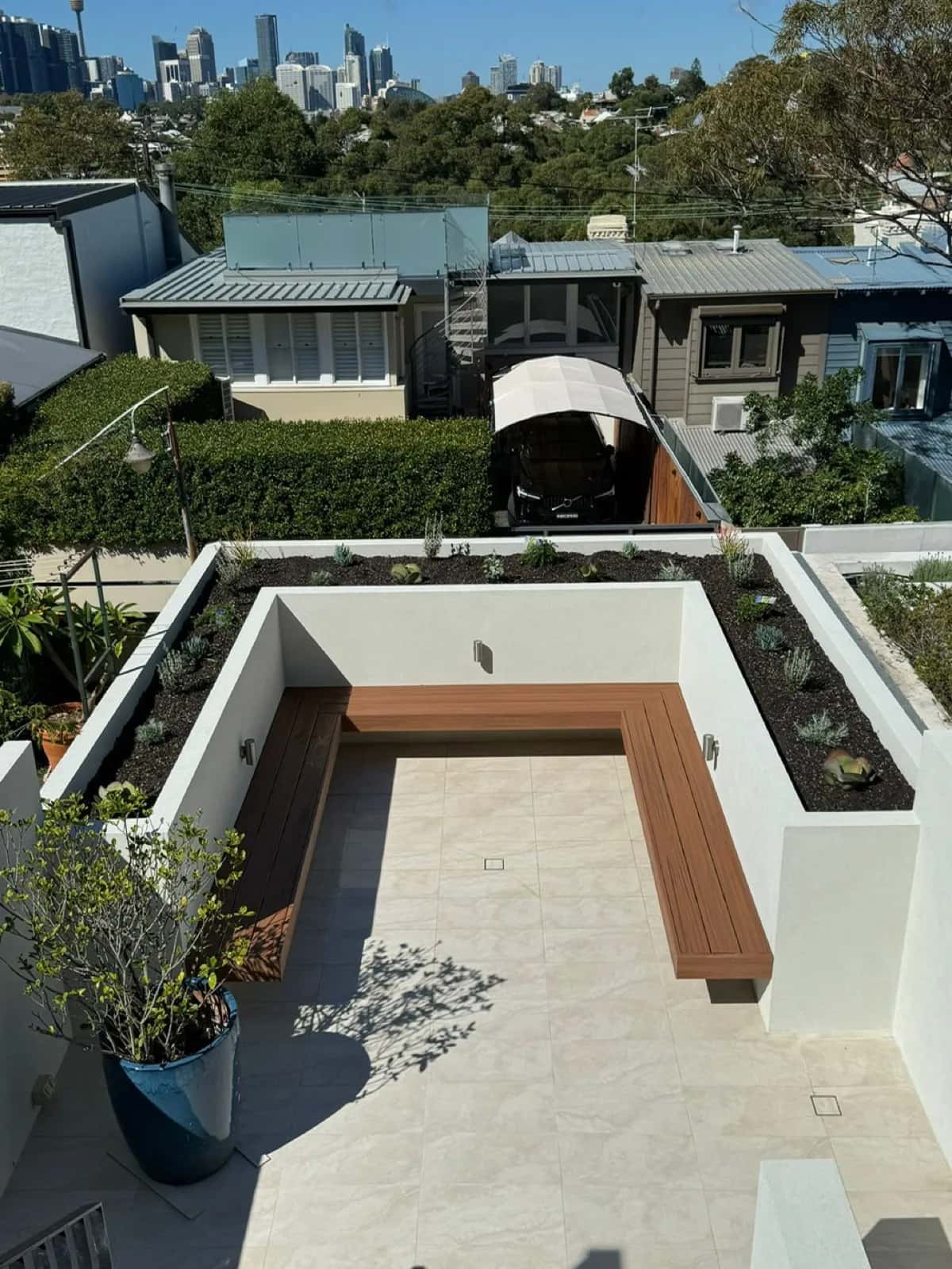 Overhead view of terrace with L-bench and planters, city skyline