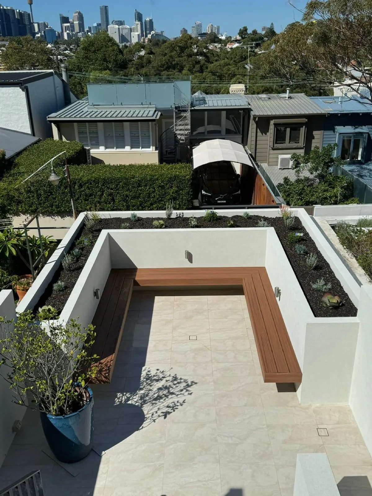 Overhead view of terrace with L-bench and planters, city skyline