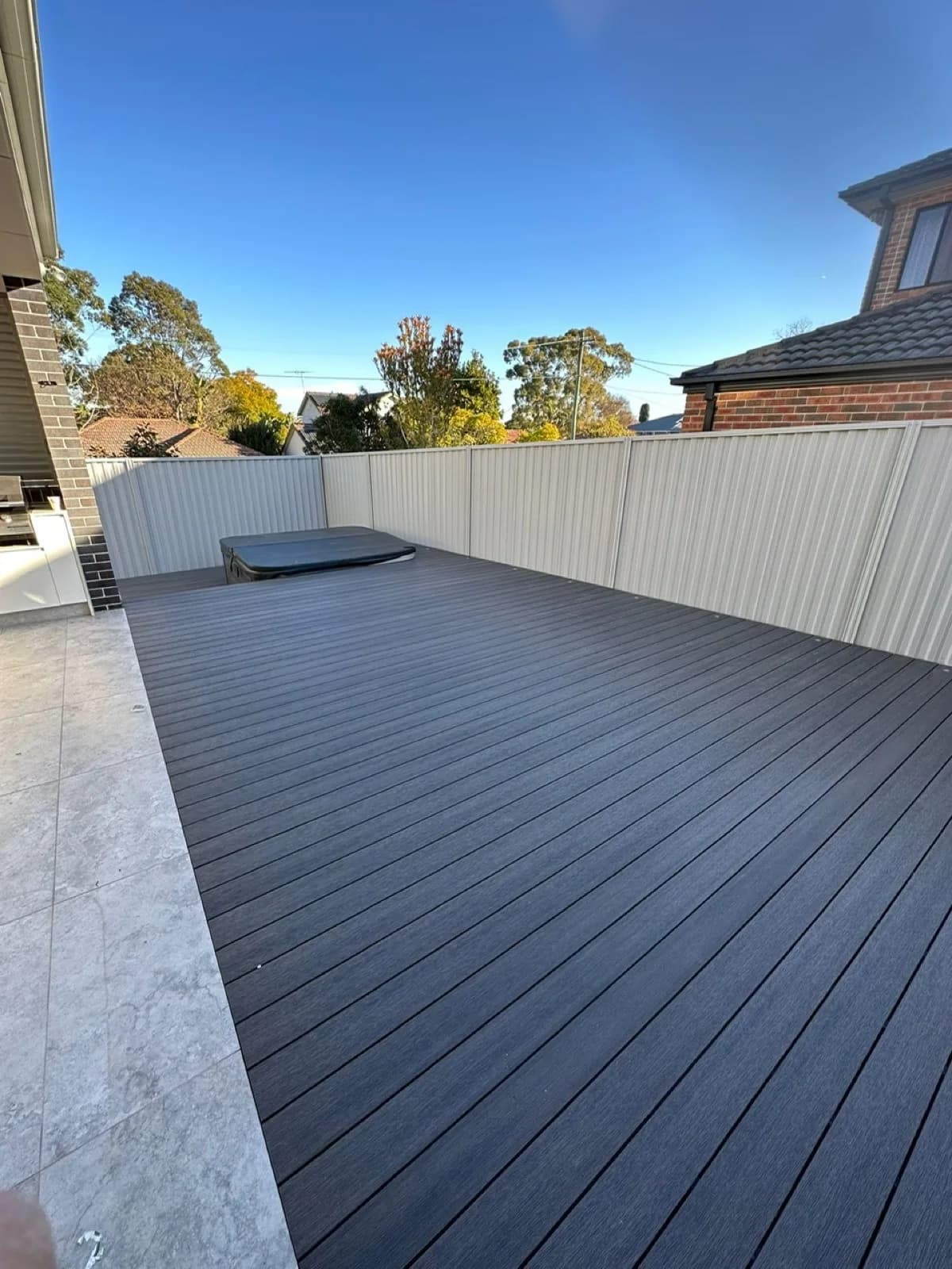 Wide view of grey deck with spa, Colorbond fences