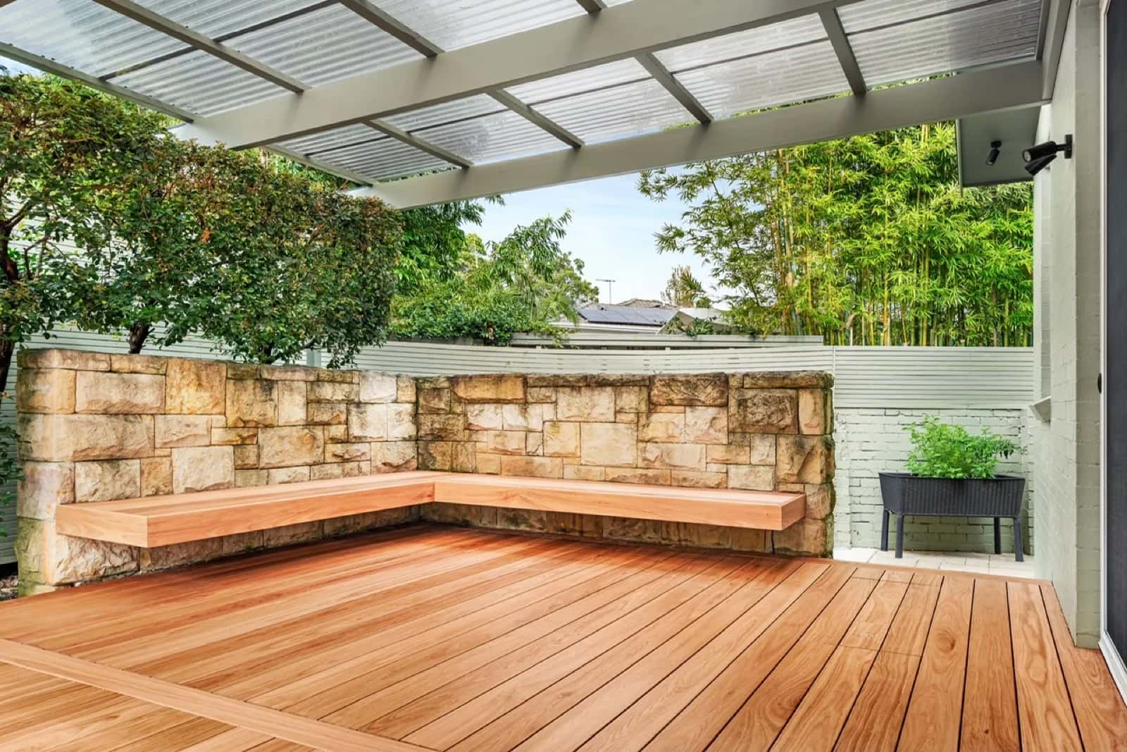 Covered deck with L-shaped floating bench along sandstone wall