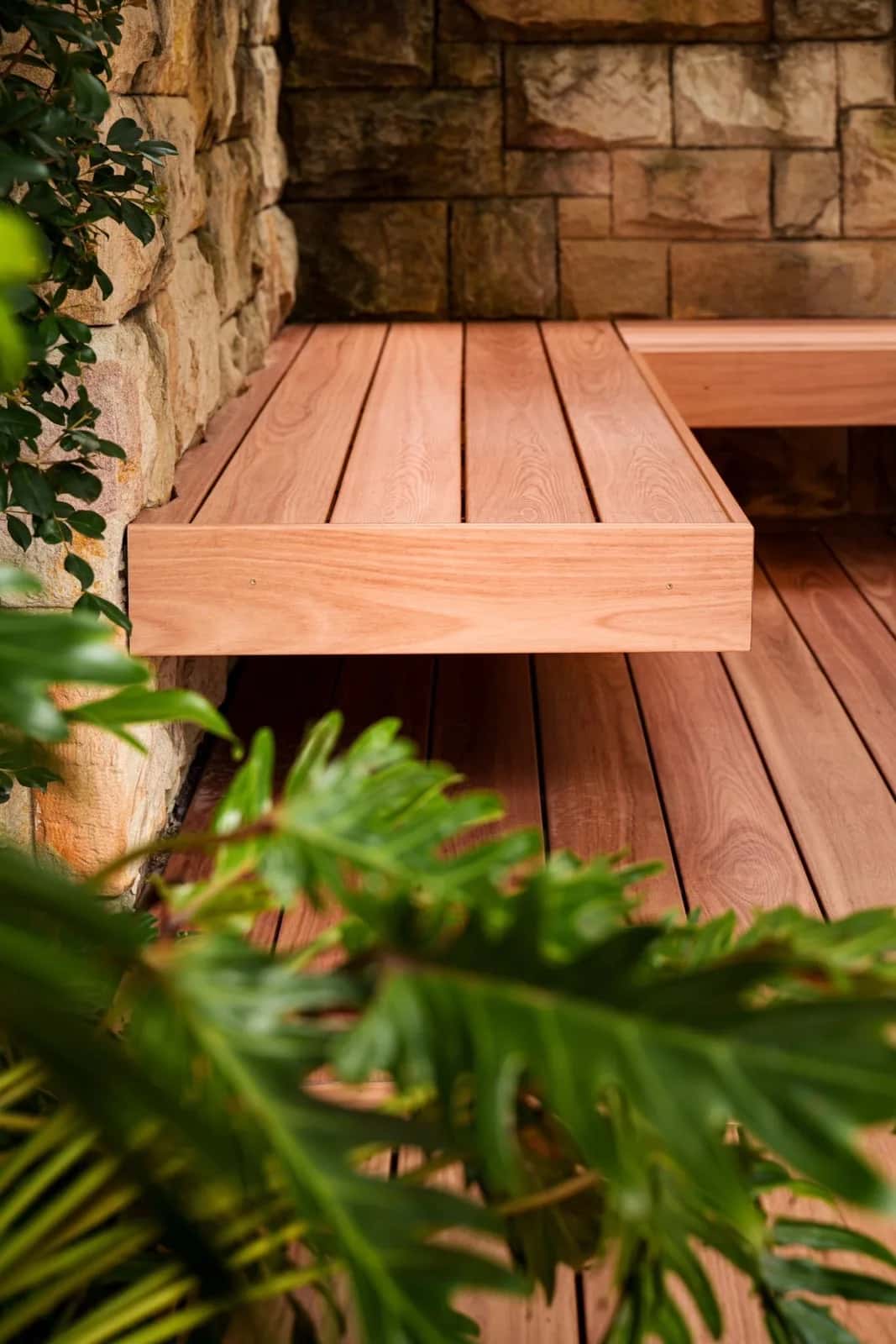 Floating timber bench against sandstone wall, close-up
