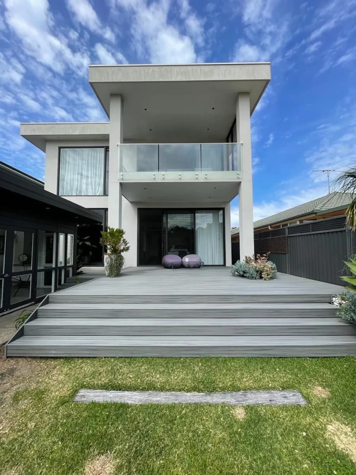 Rear of modern two-storey house with grey deck and wide steps