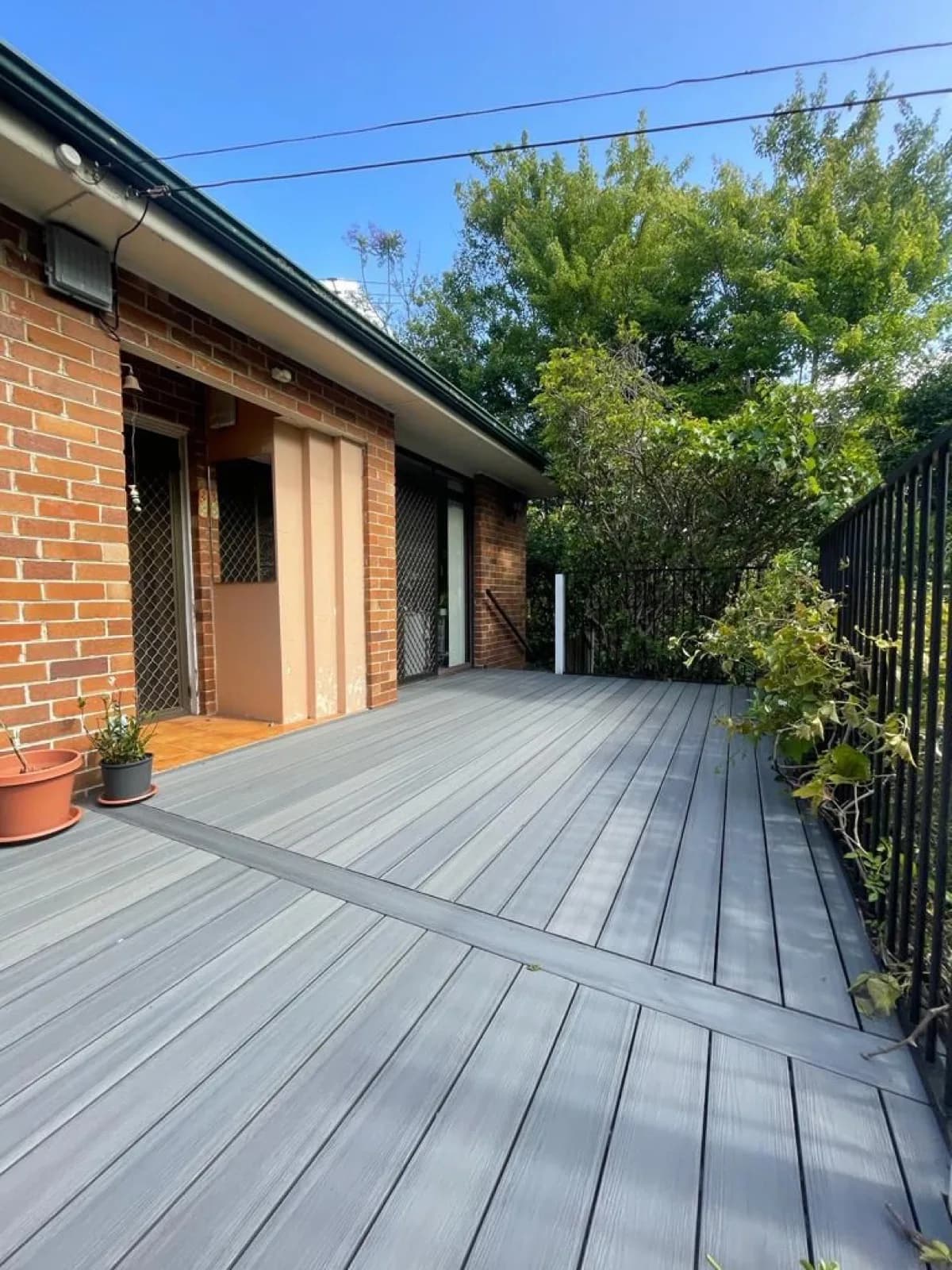 Grey composite deck with breaker board, black balustrade, brick house